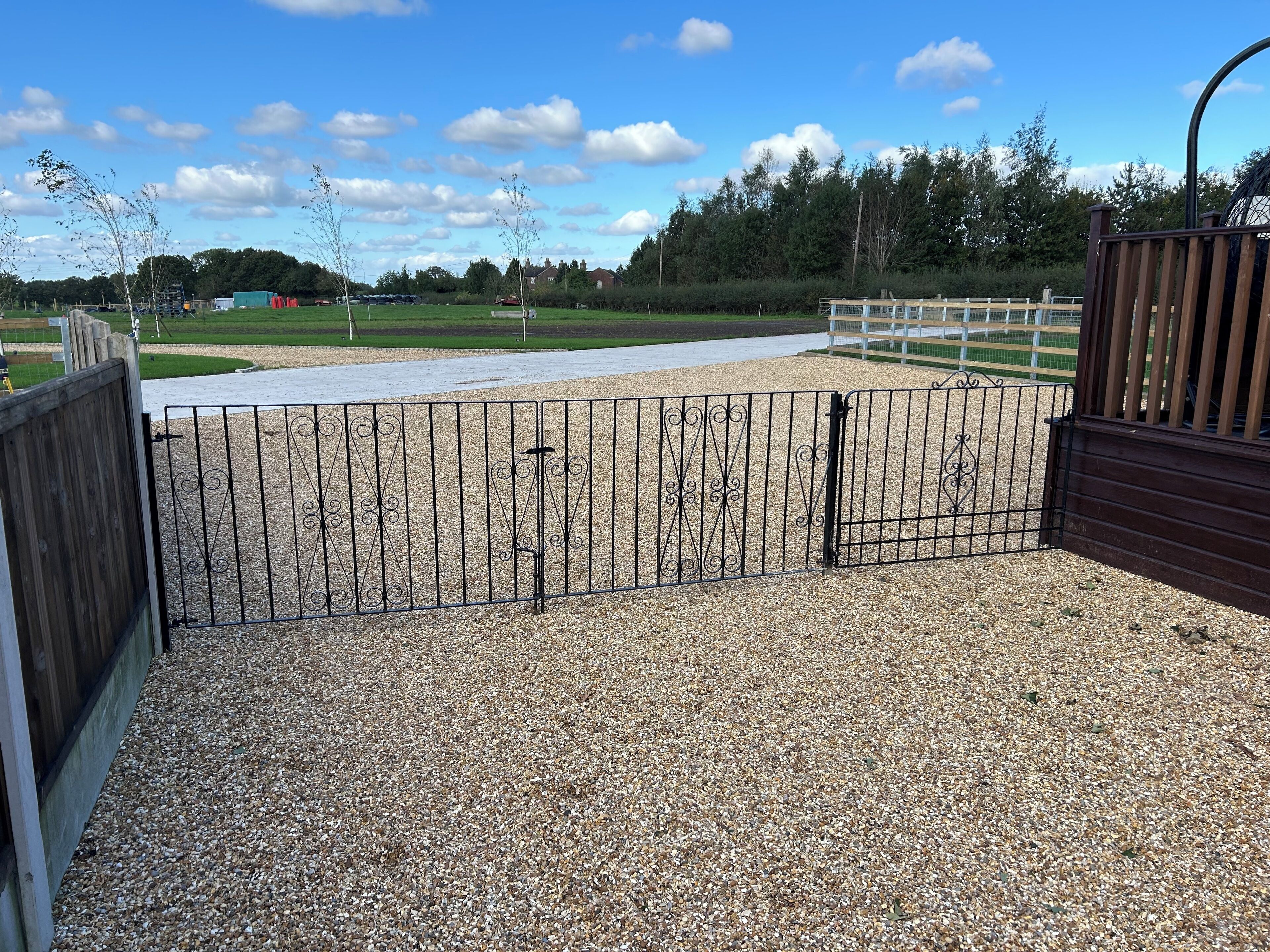 A gravel path leading to a gated area with a wooden fence and metal gate.