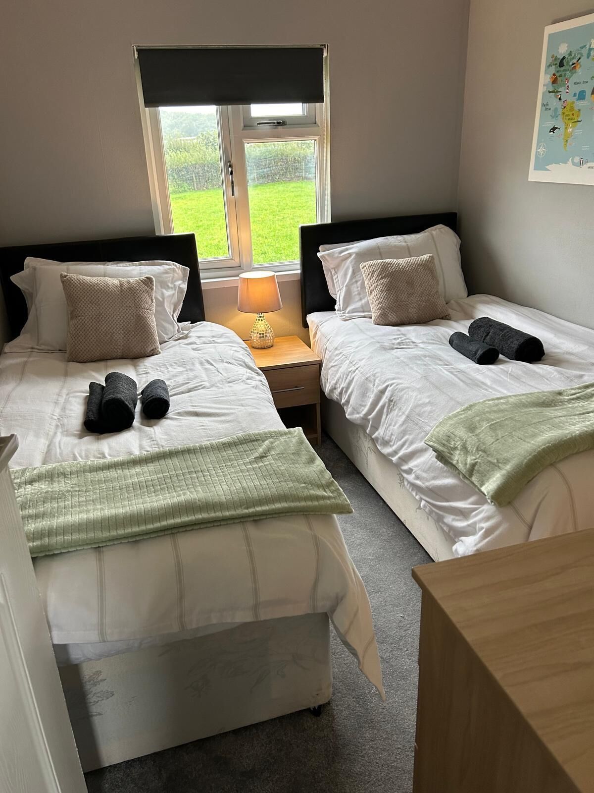 A double room with two beds, each with a pillow, a bedside lamp, and towels.