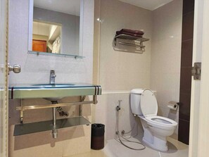 A bathroom with a glass sink, a toilet, a trash bin, and a towel rack. - Collection O VResotel (Nonthaburi)