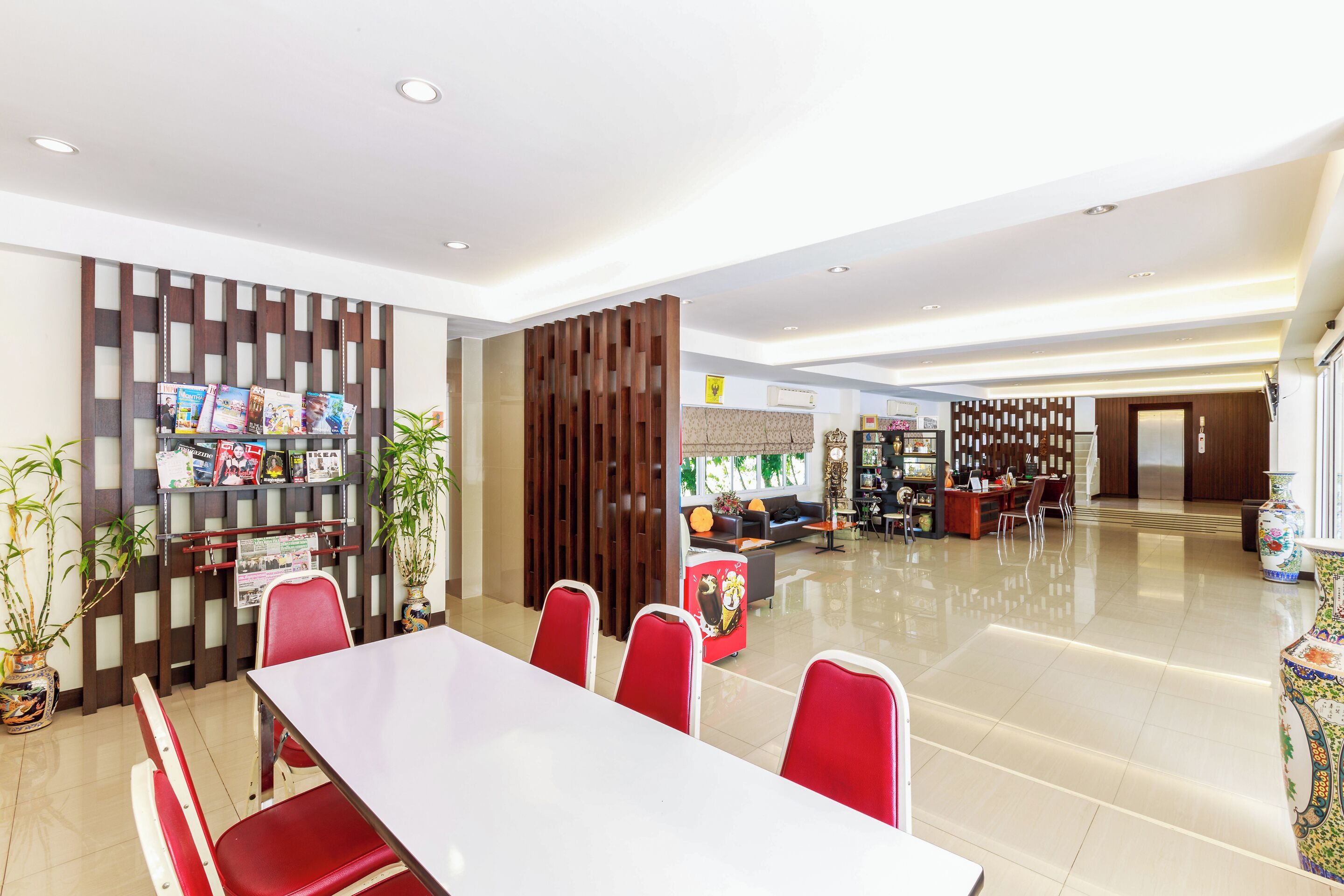 A modern hotel lobby with a reception desk, seating area, and a magazine rack.