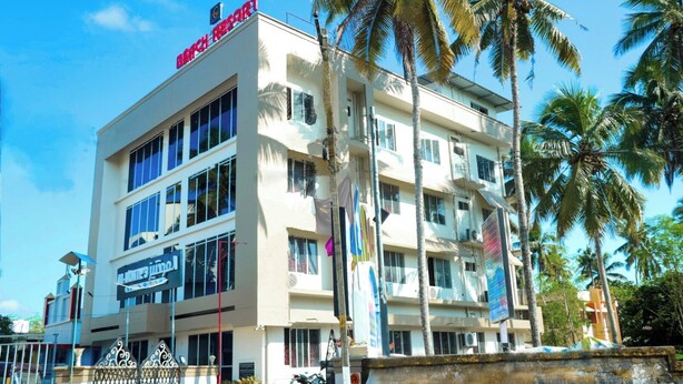 A multi-story hotel with a prominent red sign at the top. - Grand Harmony Beach Resort (Neyyattinkara)