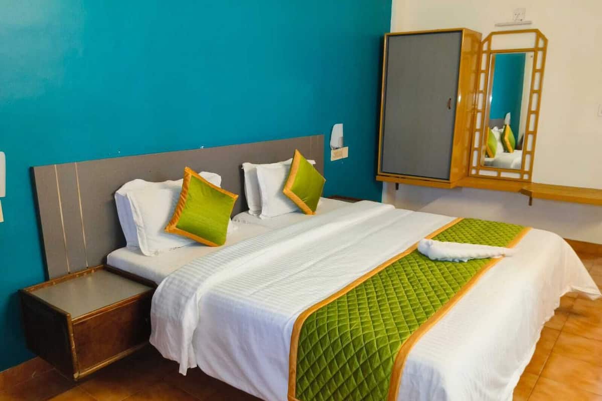 A hotel room with a bed, a nightstand, a mirror, and a wardrobe.