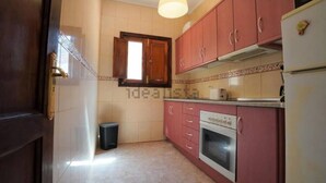 A kitchen with pink cabinets, a white refrigerator, and a window above the sink. - House La Cabaña Galdar (Galdar)