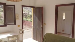A bedroom with a bed, a desk, and chairs. There is a large window and a door leading outside. - House La Cabaña Galdar (Galdar)