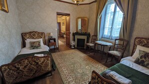A traditional room with two beds, a fireplace, a chandelier, and a view of the outdoors. - Renovated 17th-century château, a unique experience in the Niort countryside (SAIVRES)