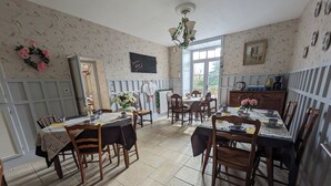 A dining area with a table set for four, surrounded by wooden chairs. A chandelier hangs from the ceiling, and a window provides natural light. - Renovated 17th-century château, a unique experience in the Niort countryside (SAIVRES)