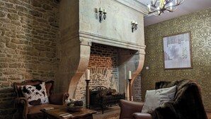 A rustic room with stone walls, a fireplace, leather furniture, and a chandelier. - Renovated 17th-century château, a unique experience in the Niort countryside (SAIVRES)