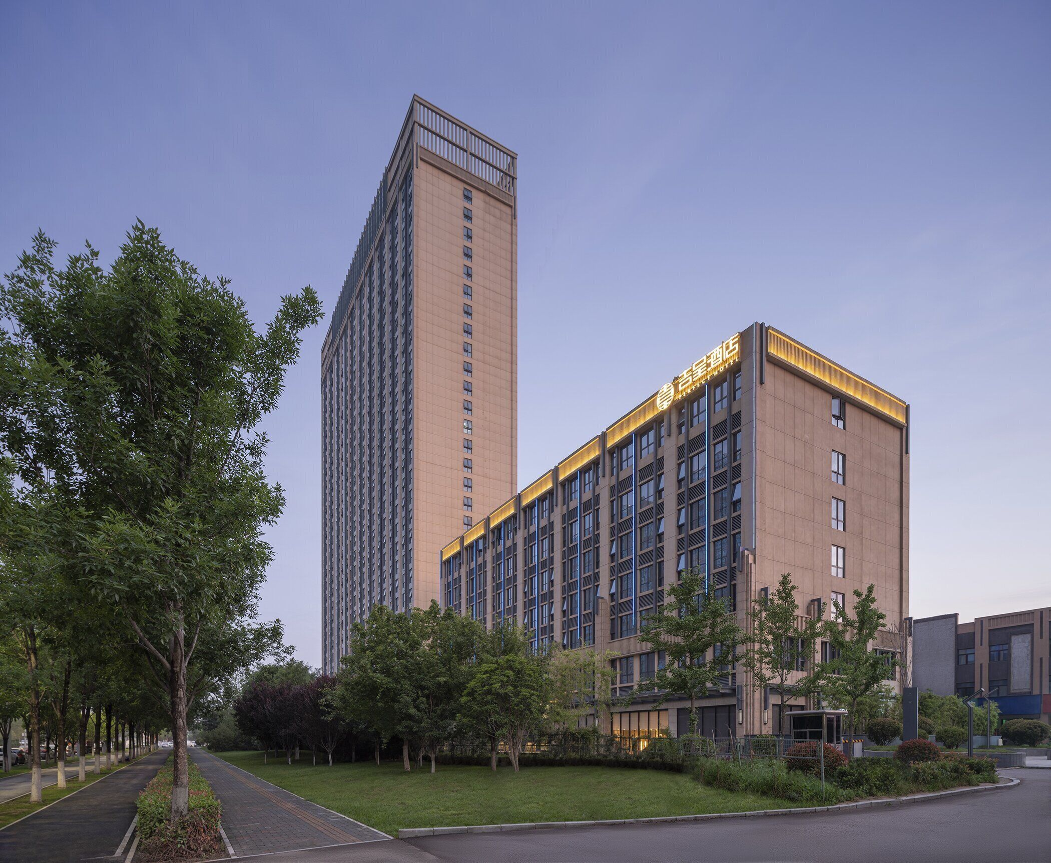 A modern hotel with a prominent tower and a shorter building with illuminated signage.