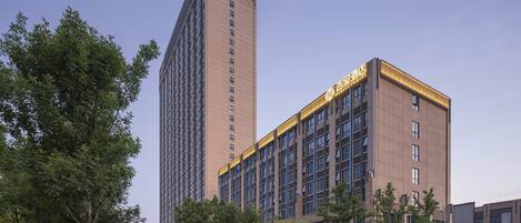 A modern hotel with a prominent tower and a shorter building with illuminated signage.