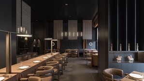A modern dining area with long tables, chairs, and ambient lighting.