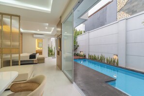 Un intérieur moderne avec un mur de verre donnant accès à un espace extérieur doté d’une piscine.