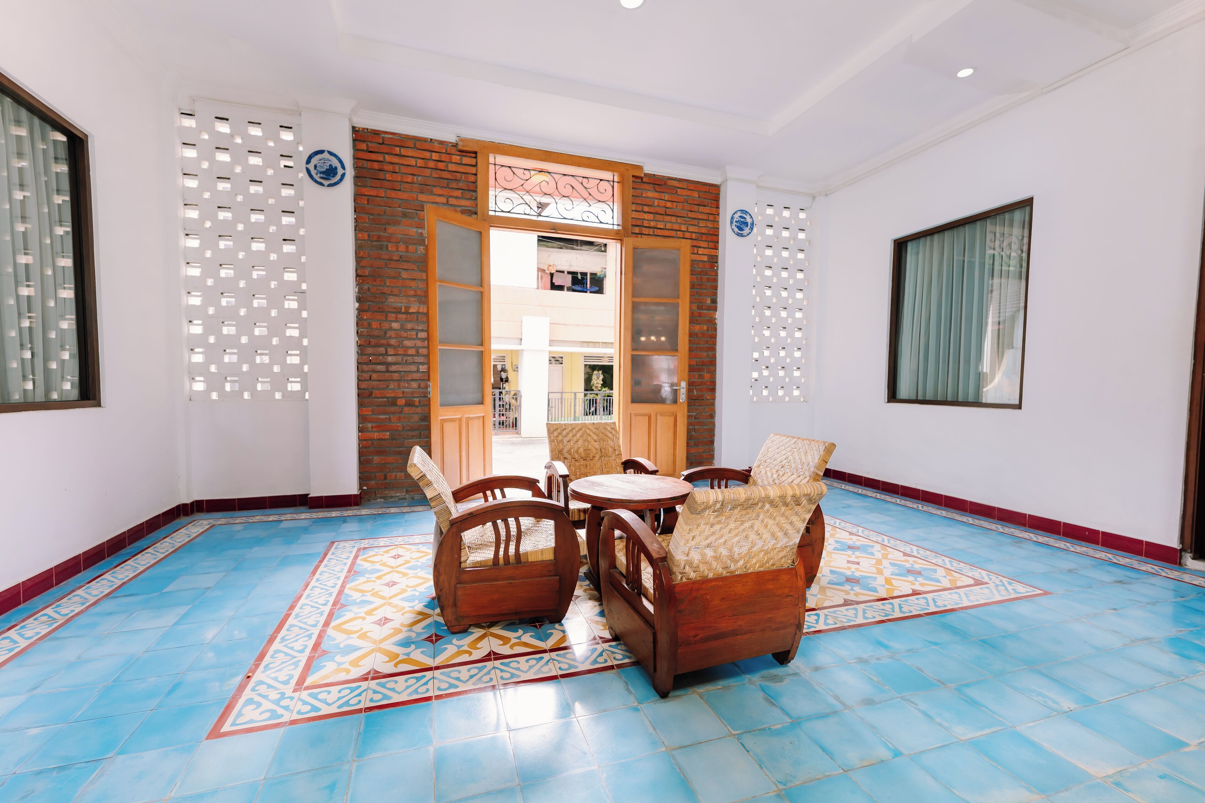A room with a blue tiled floor, wooden furniture, and a view through a glass door.