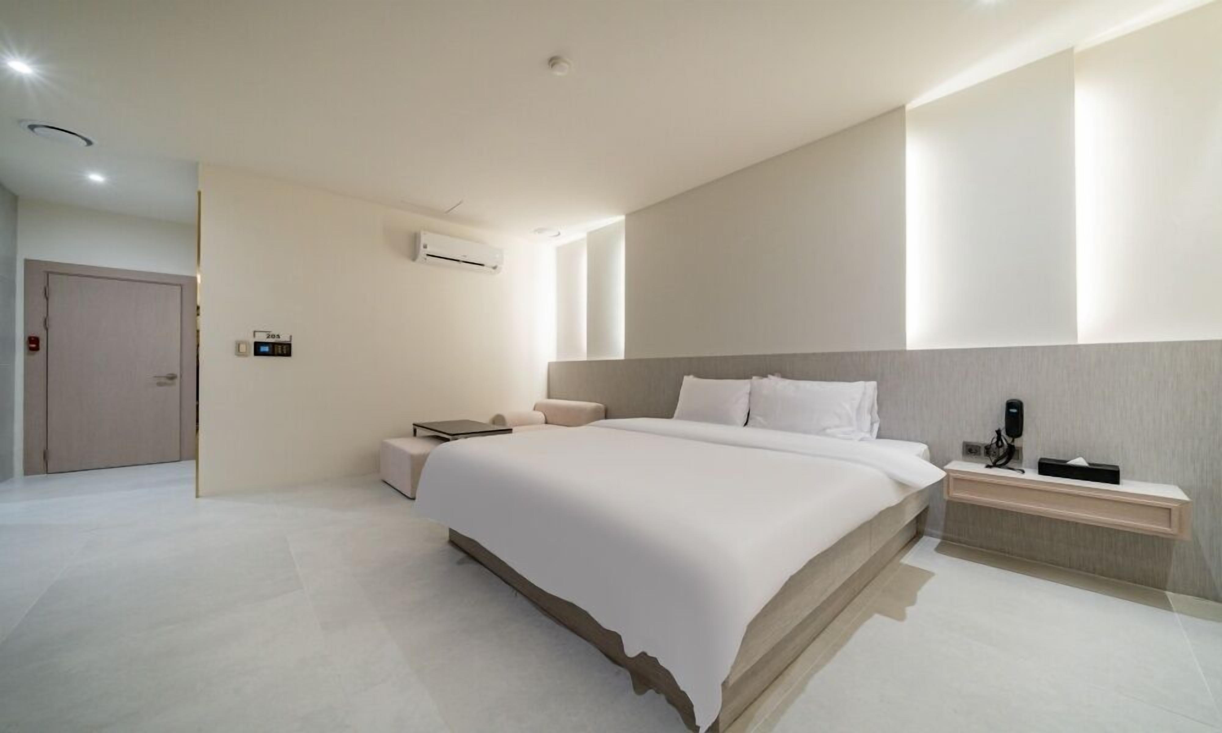 Una habitación de hotel moderna con una cama grande, mesitas de noche, un escritorio y un equipo de aire acondicionado.