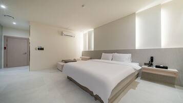 Una habitación de hotel moderna con una cama grande, mesitas de noche, un escritorio y un equipo de aire acondicionado.