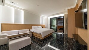 Una habitación de hotel moderna con una cama, un sofá, un banco y un puerta corredera de vidrio que da a un balcón.