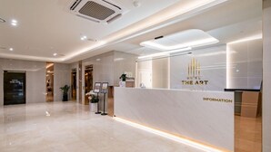 Zona de recepción de un hotel con diseño moderno, que incluye un mostrador de recepción, un panel informativo digital y un suelo limpio y pulido.