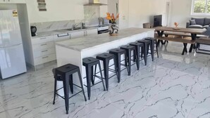 A modern kitchen with a marble countertop, black bar stools, and a central island. - Te Aro Villa 2
Modern Brand New 3brm villa with pool in Muri (Ngatangiia District)