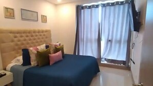 Een slaapkamer met een bed, nachtkastje, plafondventilator en een raam met gordijnen.