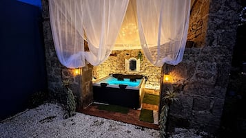 Un edificio de piedra con jacuzzi, cortinas blancas y paredes de piedra.