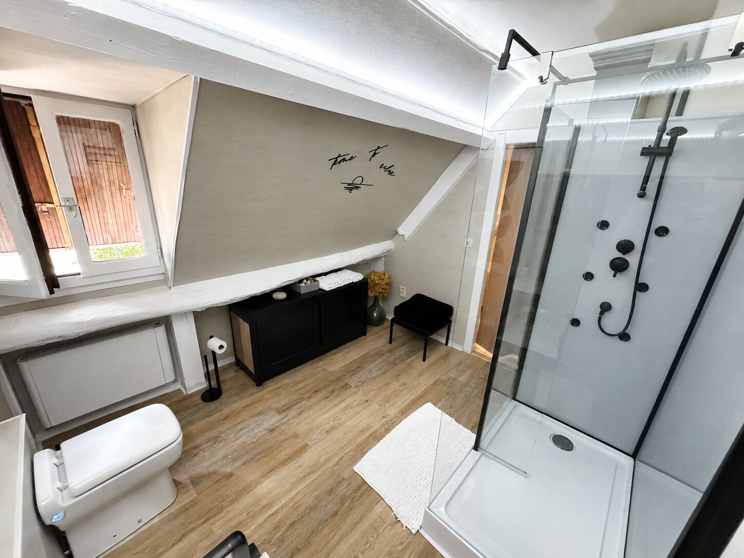 A compact bathroom with a shower, toilet, and a small vanity area.