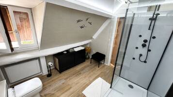 A compact bathroom with a shower, toilet, and a small vanity area.