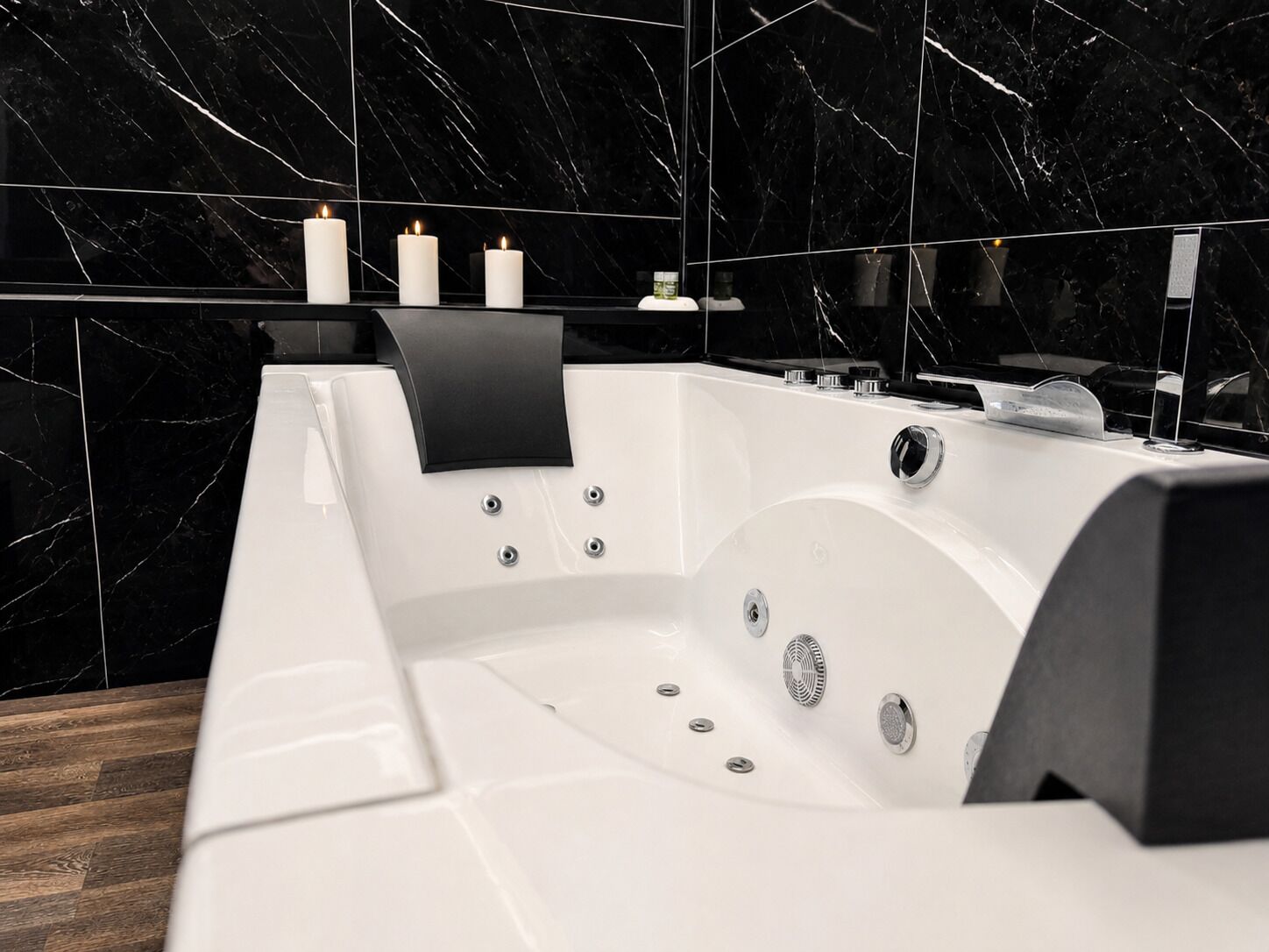 A modern bathroom with a black marble backsplash, a white bathtub, and a black towel rack.