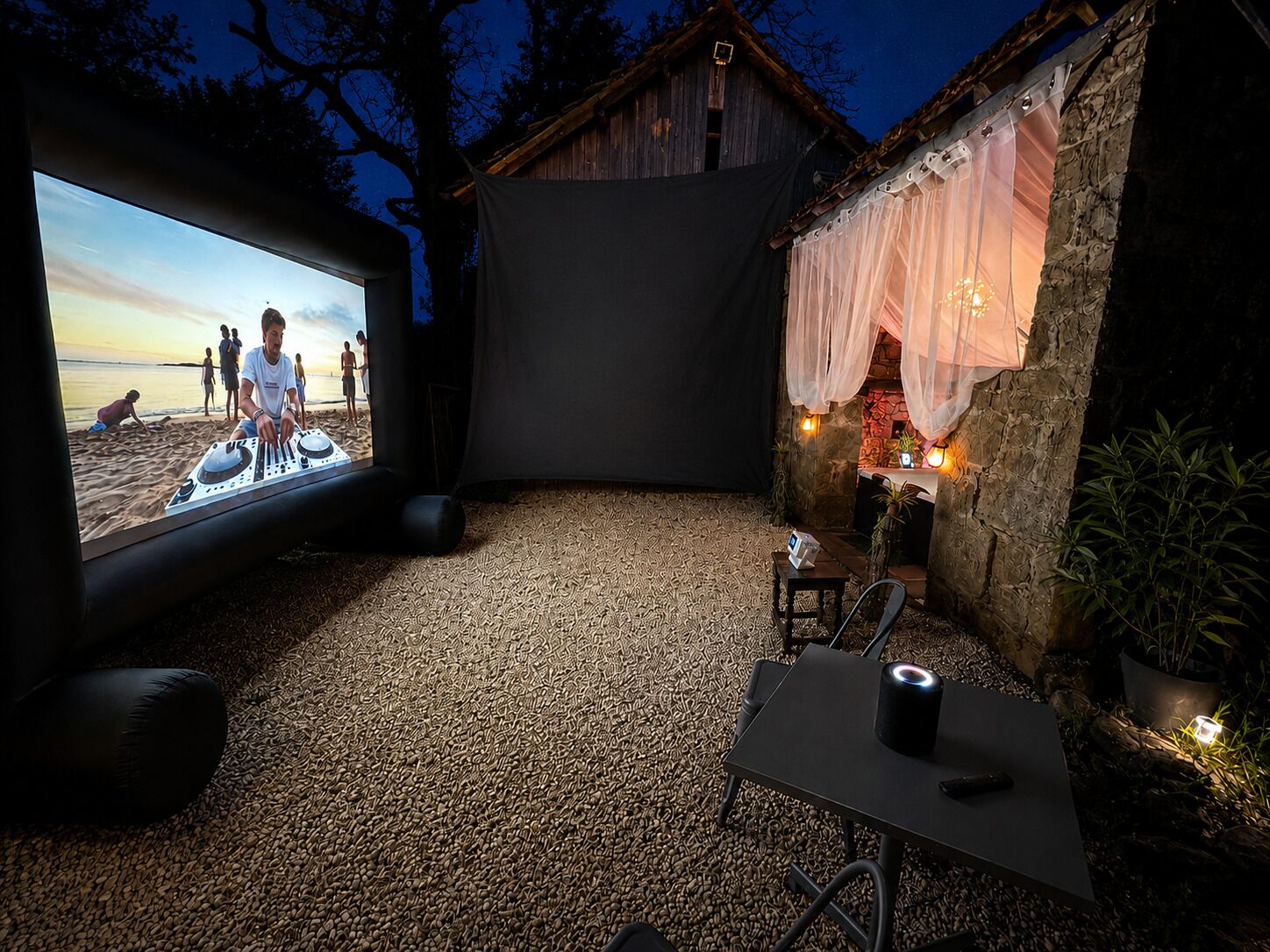 Un cinéma en plein air doté d’un grand écran, d’une cabine de DJ et d’un espace de détente confortable avec des tables et des chaises.