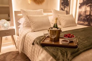 A bed with a champagne bottle, glasses, strawberries, and chocolate in a tray. - Domaine Valenquercy (Le Vignon-en-Quercy)