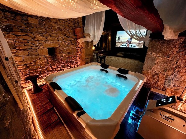 Une pièce aux murs de pierre, dotée d’un jacuzzi, d’un plancher en bois et offrant une vue sur la plage.