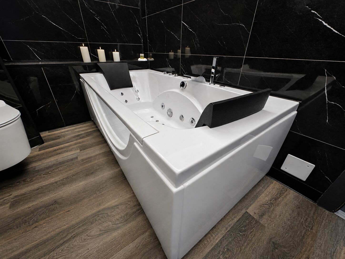 A modern bathroom with a large white bathtub, a toilet, and a vanity with a mirror.