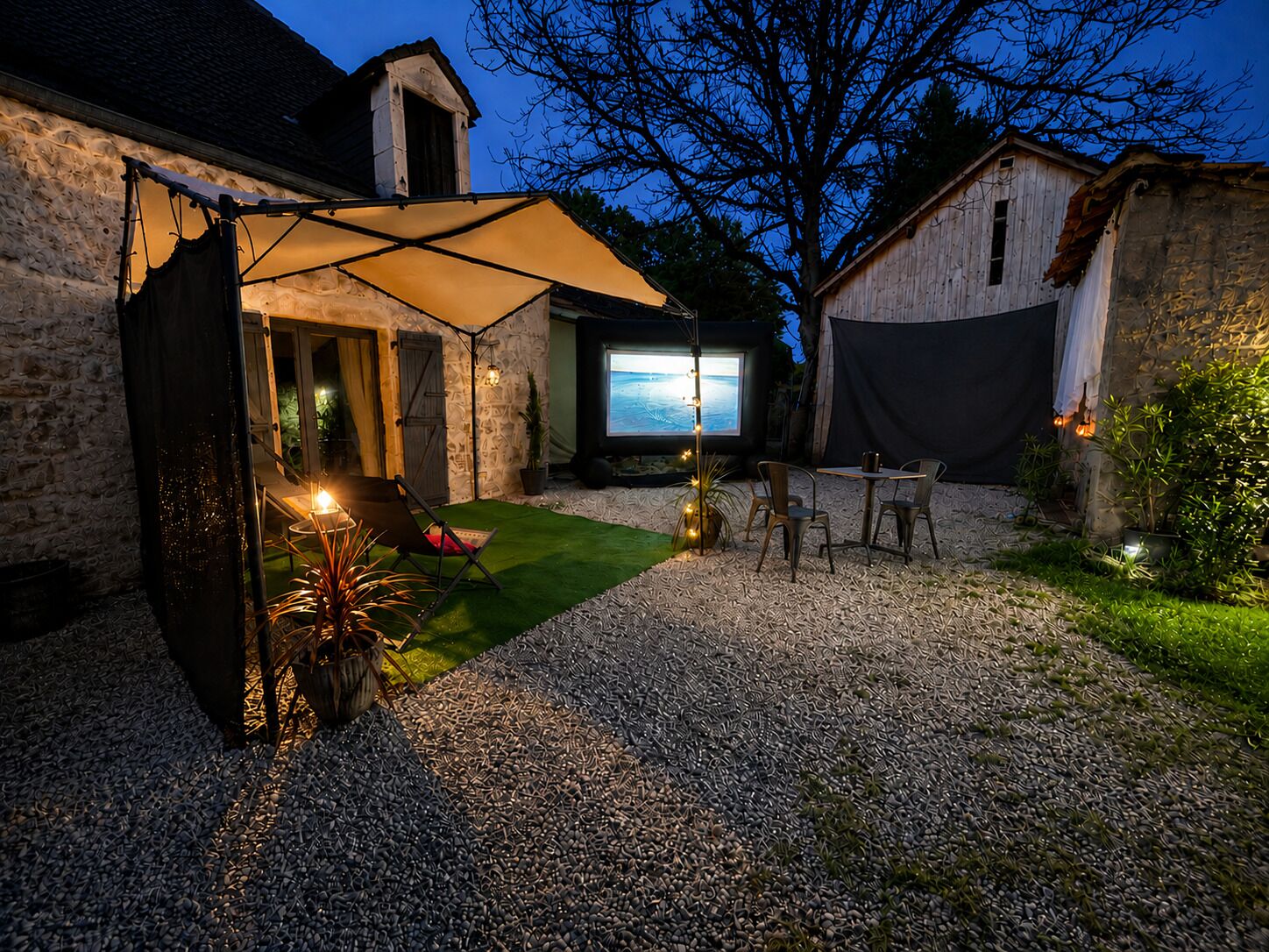 A patio area with a table and chairs, a projector screen, and a tent.