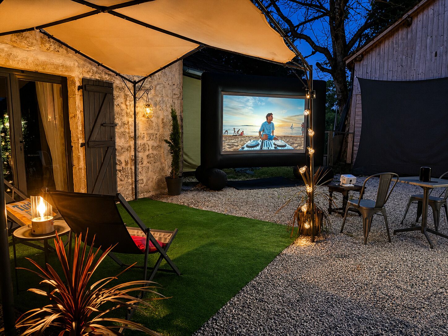 Eine Terrassenanlage im Freien mit Projektionsleinwand, Sitzgelegenheiten und einer kleinen Bühne.