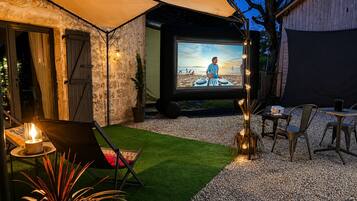 An outdoor patio with a projector screen, seating, and a small stage.