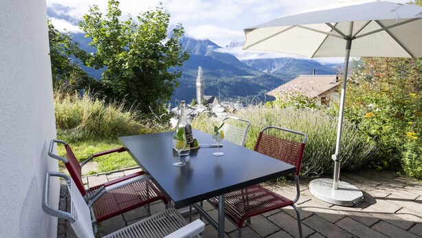 Eine Terrasse im Freien mit Tisch und Stühlen, einer Weinflasche und einem Weinglas.