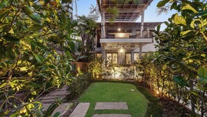 A modern house with a two-story structure, a covered patio, and a well-maintained garden with a lawn and stone pathway. - White Cove Retreat, Noosa Heads (Noosa Heads)