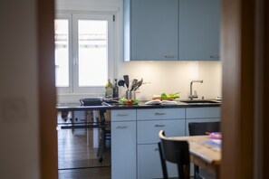 A modern kitchen with light blue cabinets, a stainless steel stove, and a wooden dining table.