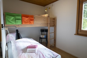 Un lit superposé avec une échelle, une table de chevet et une chaise.