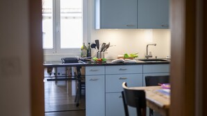 Une cuisine moderne avec des meubles de couleur bleu clair, une cuisinière en acier inoxydable et une table à manger en bois.