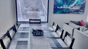 Un coin repas avec une grande table, des chaises et une vue sur un paysage enneigé par la fenêtre.