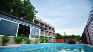 En swimmingpool med en klar, blå vandoverflade, omgivet af en flisebelagt terrasse.
