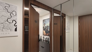 Een gang met een houten deur, een kaart aan de muur en een kastje met beeldjes.