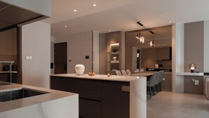 Een moderne keuken met een centraal eiland, inbouwapparatuur en een eethoek met stoelen.