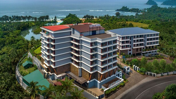 A multi-story hotel with a red roof and a sign labeled "GATEWAY." It features a modern architectural design with balconies and a view of the ocean and greenery. - Gateway Goa, Palolem (Canacona)