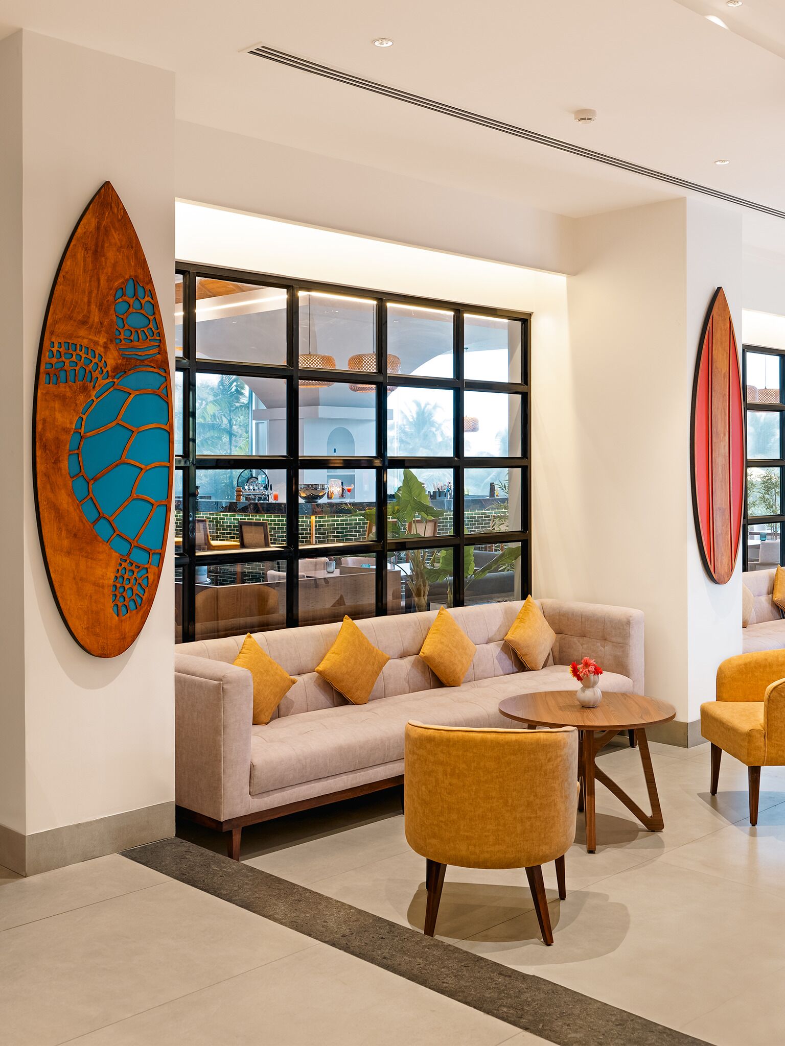 A modern lobby with a beige sofa, yellow chairs, and a large window with a view of the outdoors.