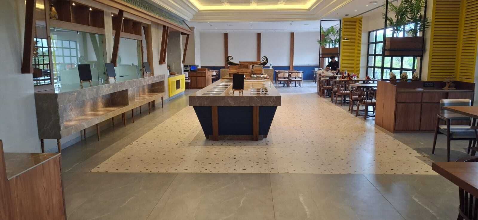 Een ruime hotel lobby met een centraal eiland, zithoeken en een receptiebalie.