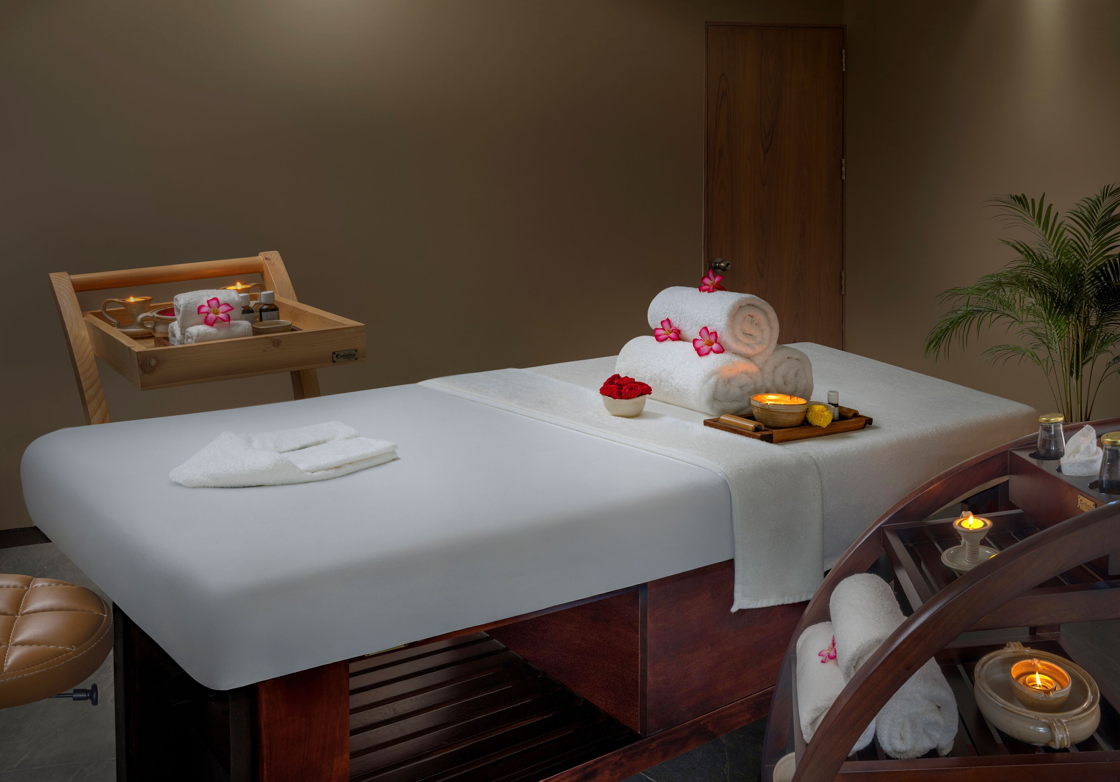 Une table de massage avec des serviettes, des bougies et un plateau contenant divers articles de confort.