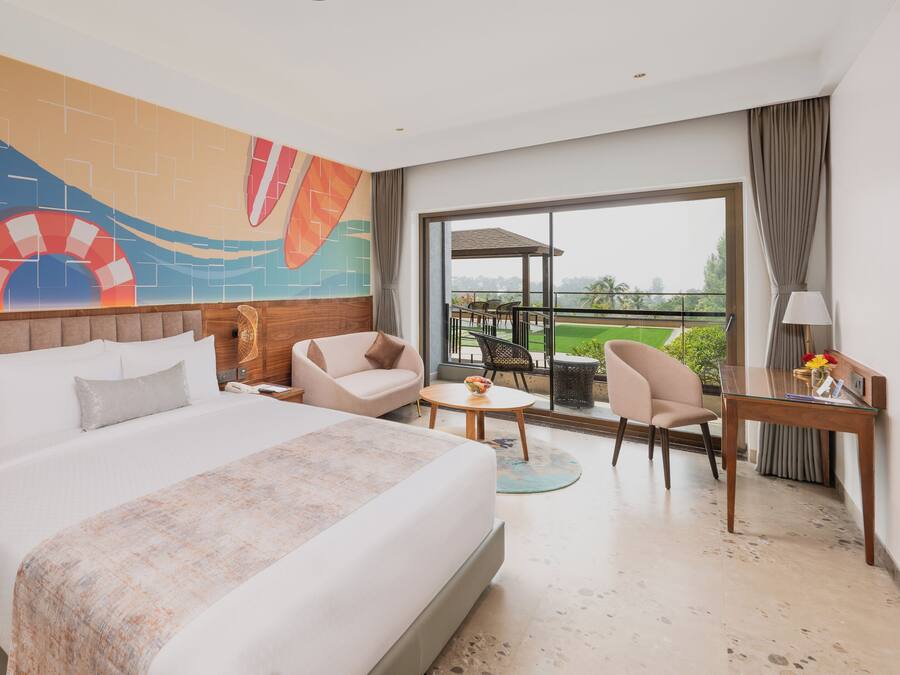 Habitación de hotel con una cama grande, un escritorio, una silla y vistas al exterior.