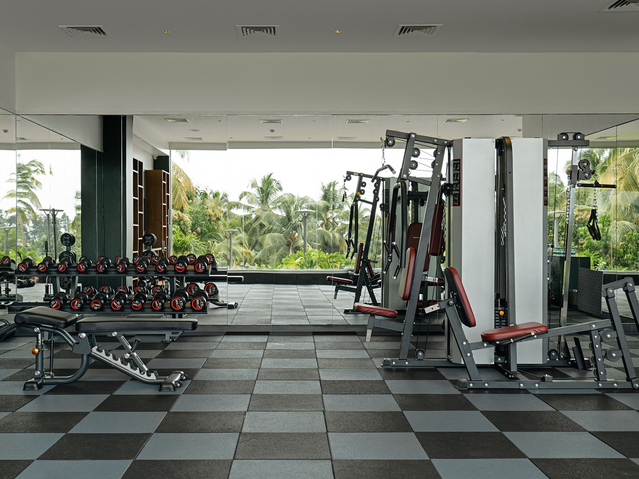 A gym with weightlifting equipment, benches, and a checkered floor.