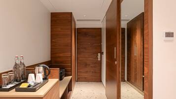 A hotel room with a wooden wardrobe, a minibar, and a coffee station.