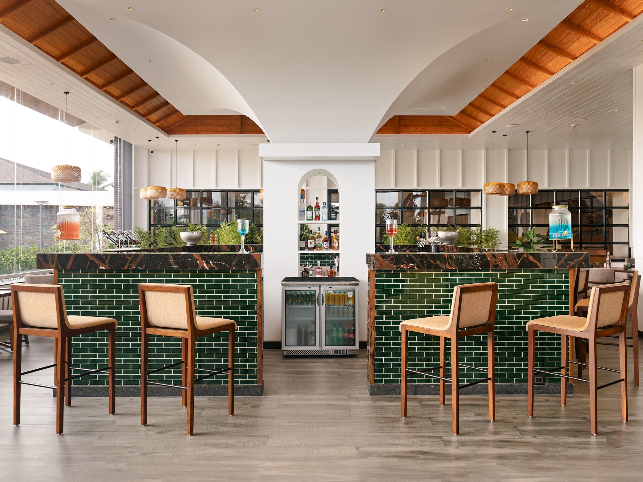 A bar area with green brick walls, wooden ceiling beams, and bar stools.